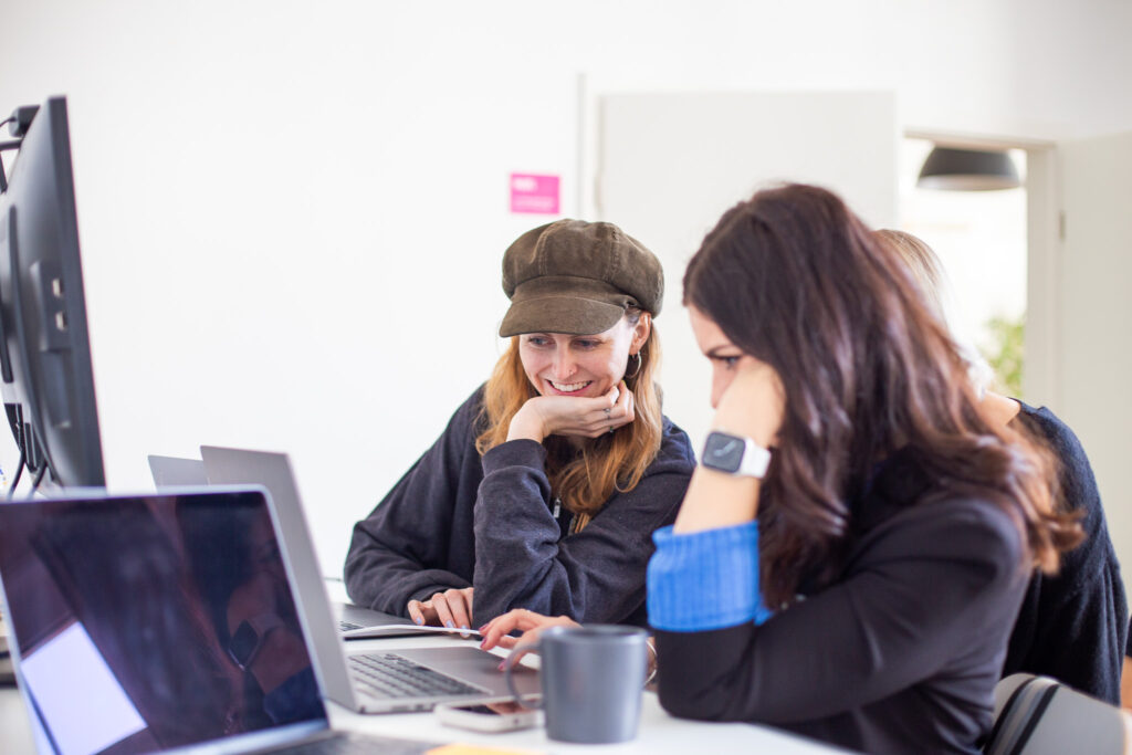 Zwei Frauen sitzen vor Laptop