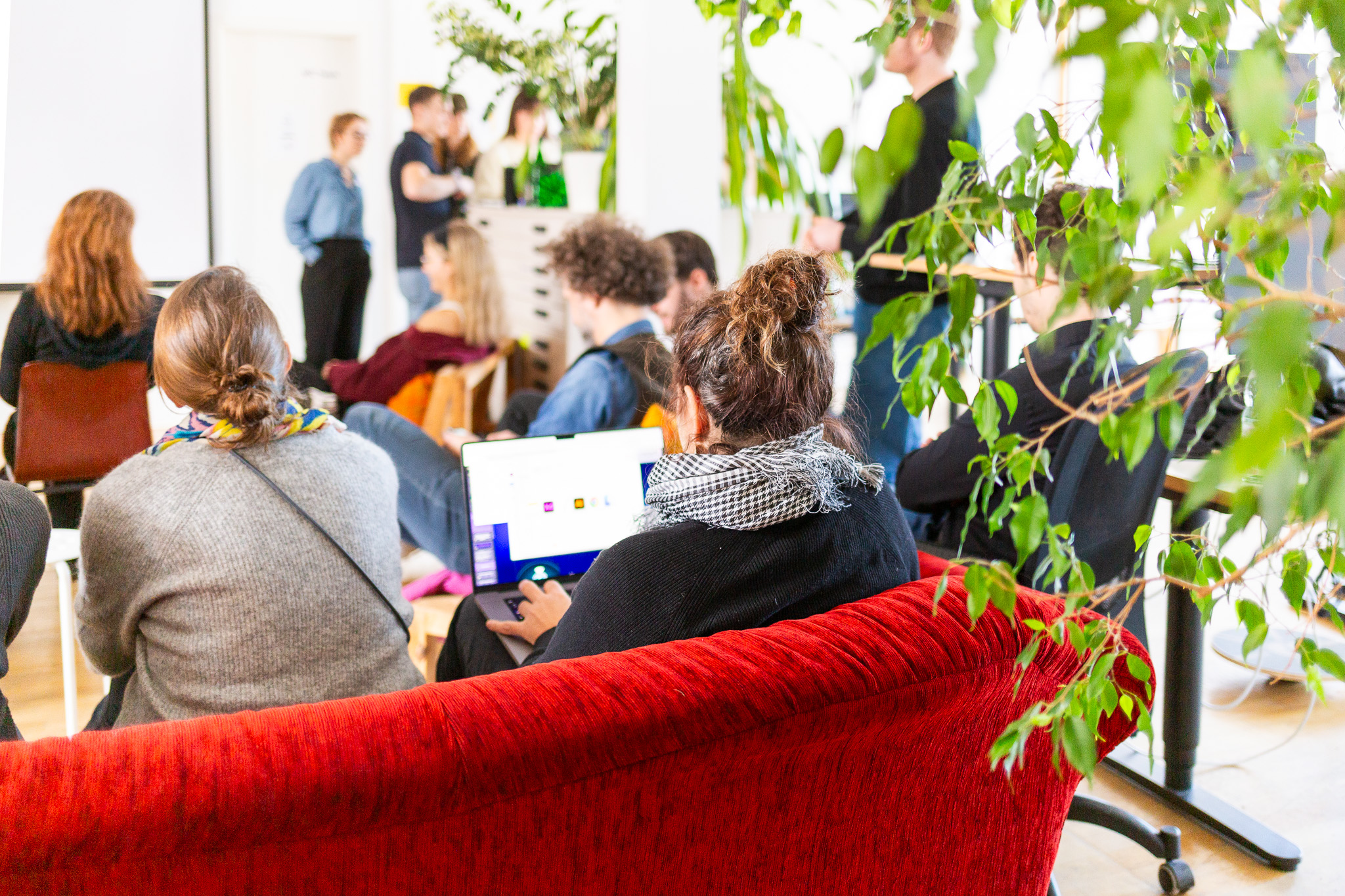 Personen sitzen in einer Masterclass auf Sofas und hören zu